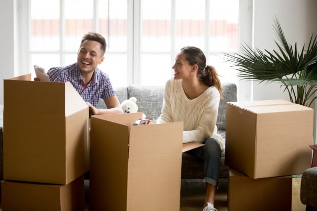 Couple laughing while unpacking from cardboard